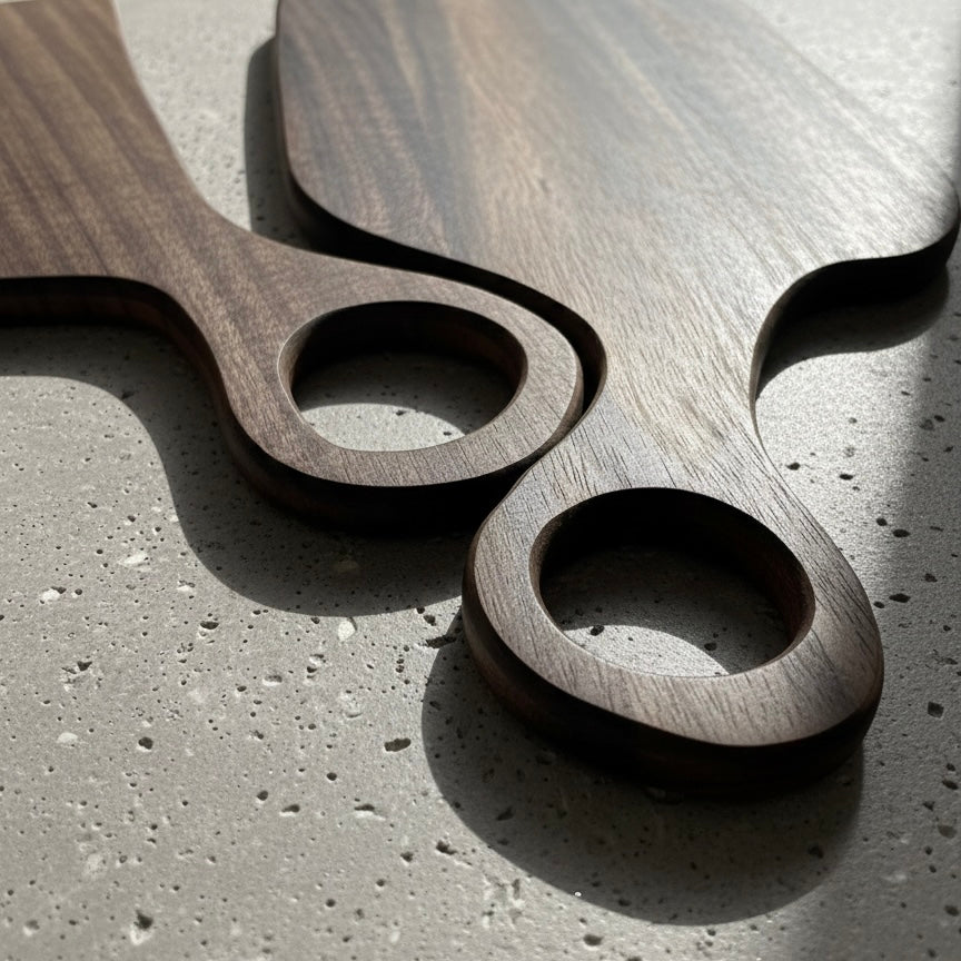 Black walnut cutting board set laid flat showing rich wood grain and looped handle detail