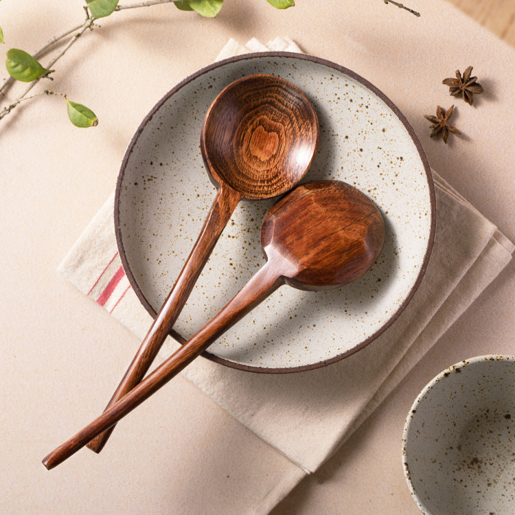 Two natural Phoebe wooden spoons on a ceramic plate with a neutral background